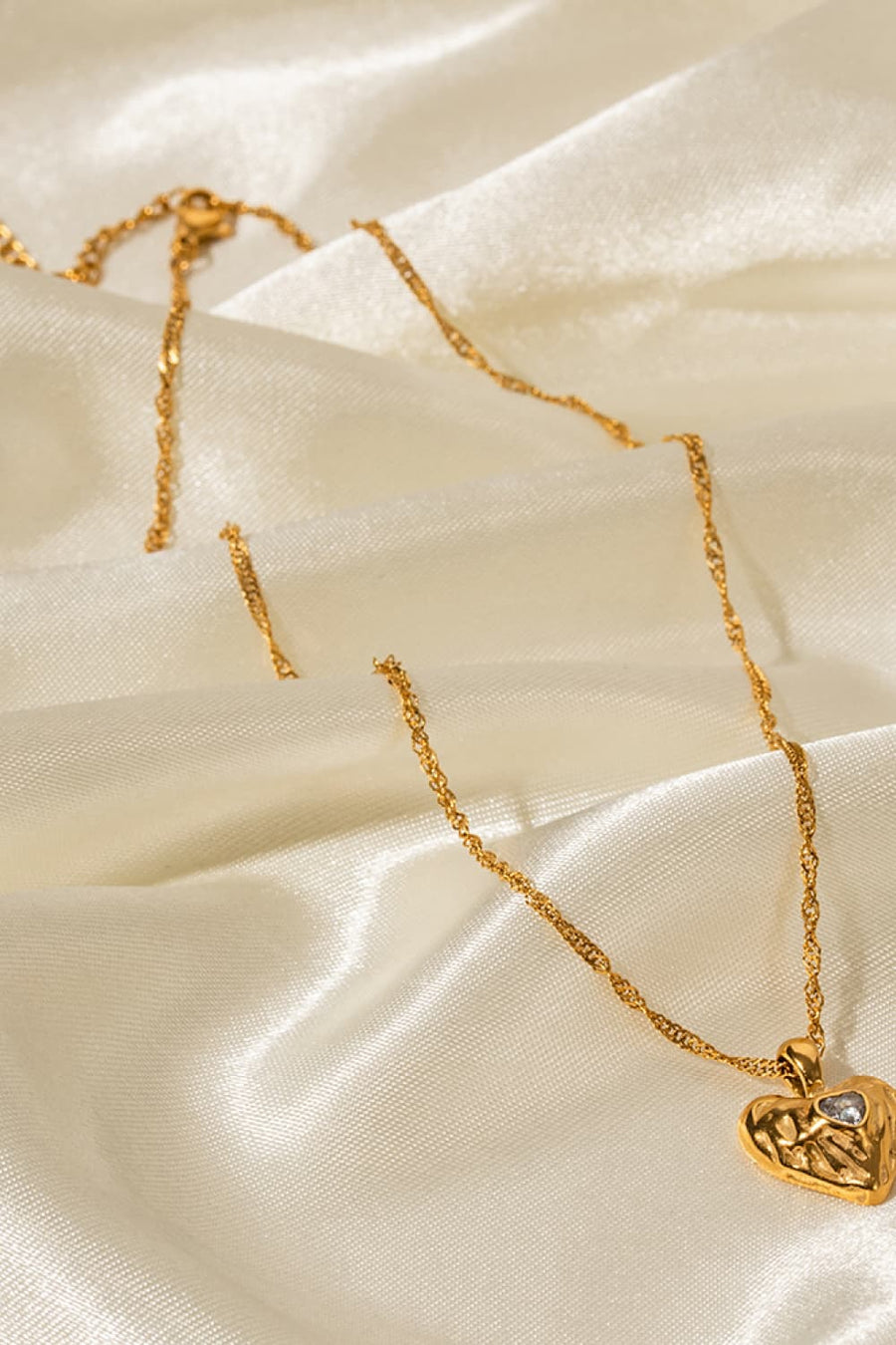 Gold textured heart pendant necklace with a clear stone detail on a delicate chain.