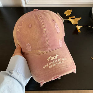 Distressed pink baseball cap with embroidered text and frayed details