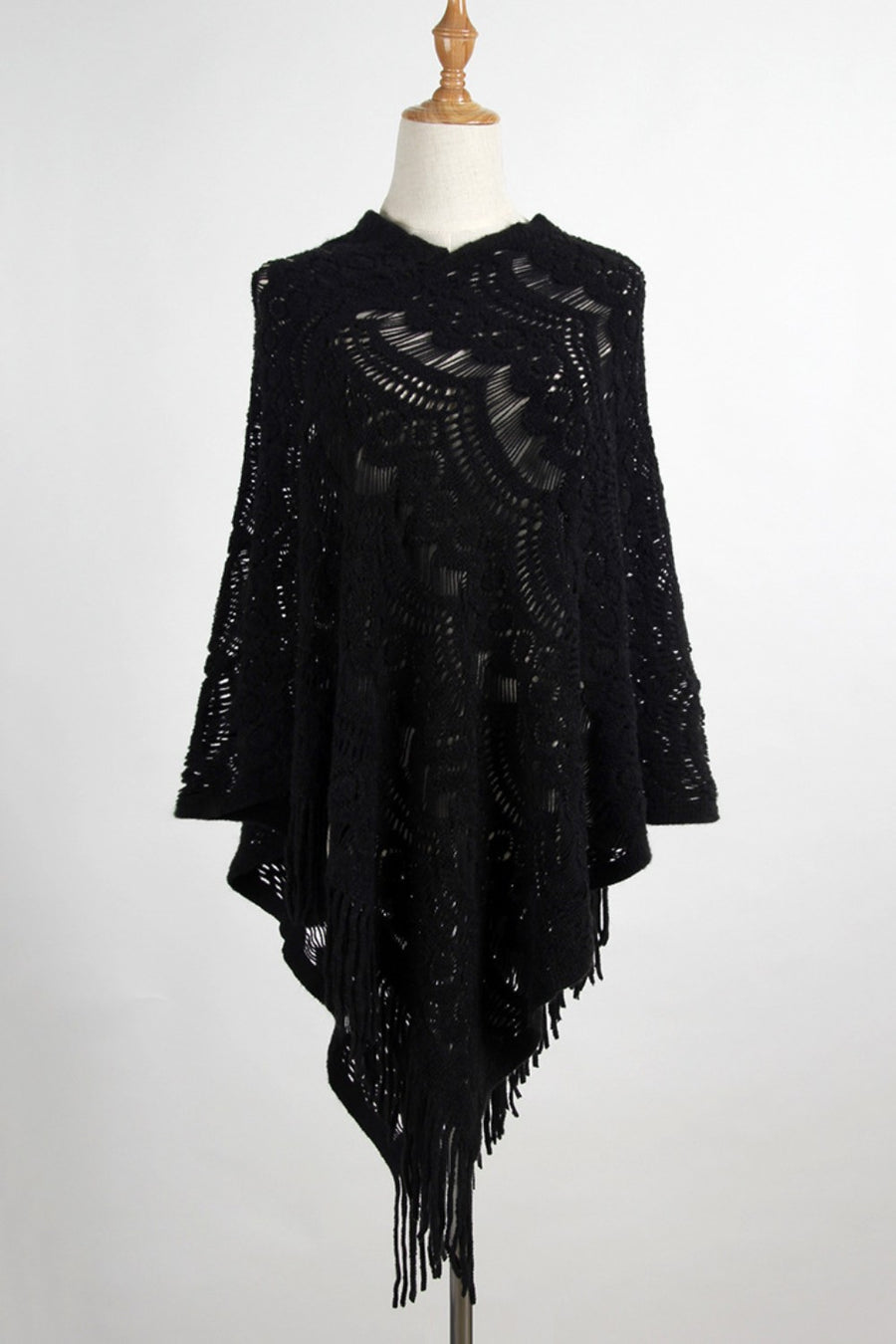 Black crochet poncho with intricate openwork pattern and fringe trim.