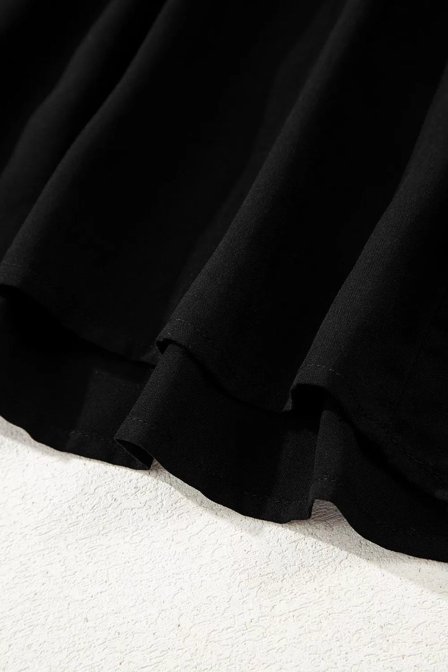 Black tiered maxi dress detail showing fabric texture and hemline