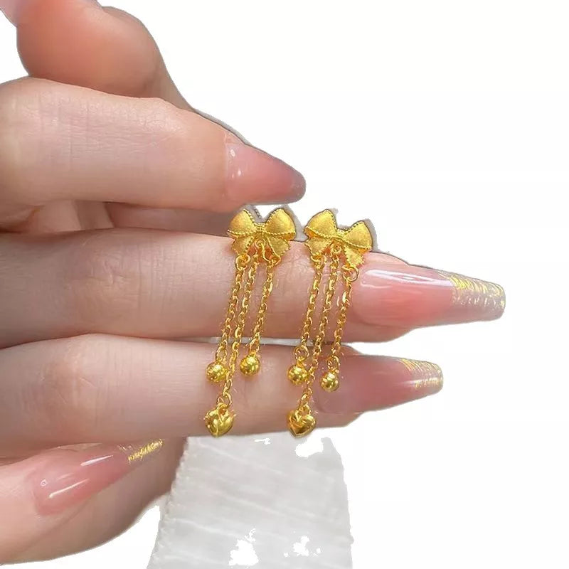 Gold bowknot tassel earrings with heart and bead charms.