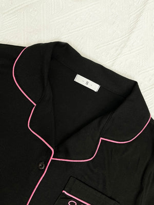 Black pajama top with pink piping and a pocket