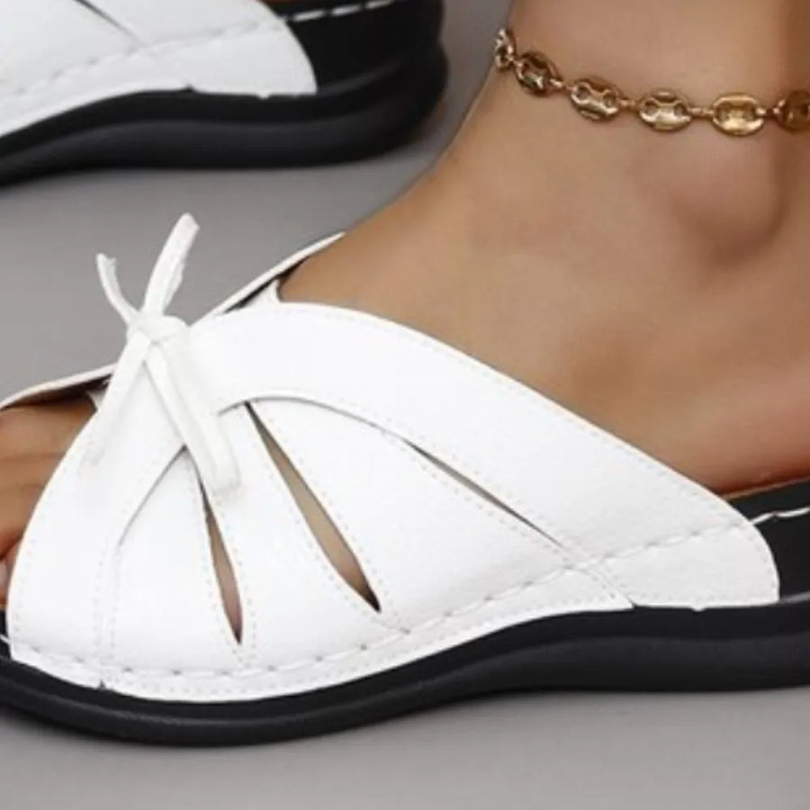 White leather lace-up cutout slides with black sole and ankle bracelet.
