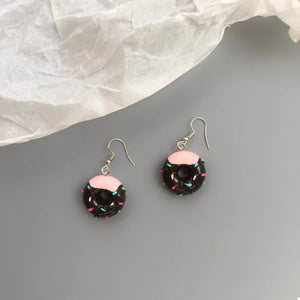 Dark brown donut dangle earrings with pink icing and colorful sprinkles.
