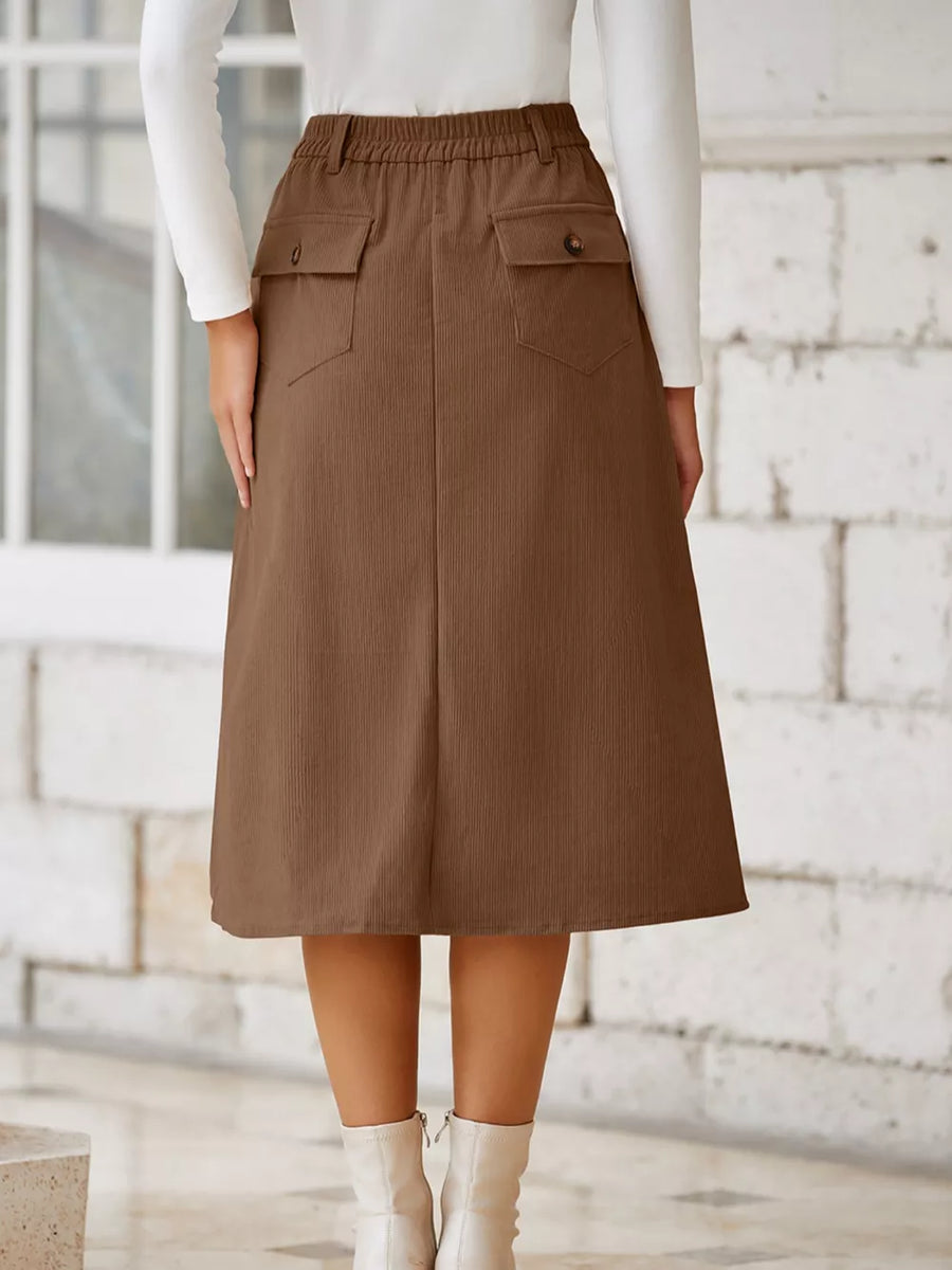 Brown corduroy midi skirt with buttoned flap pockets and elastic waistband.