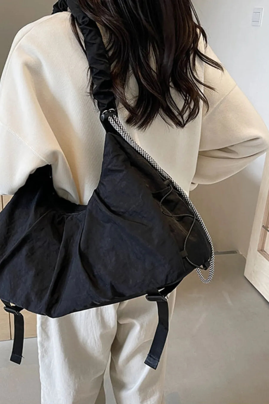 Black gathered crescent shoulder bag with ruched strap and drawstring detail