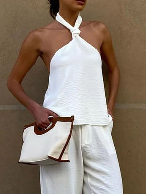 White twisted backless halter cami with textured fabric and a knotted neckline.