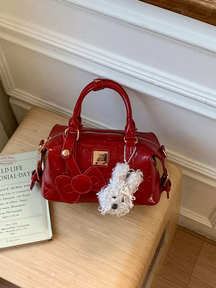 Red patent crossbody bag with bow detail and fluffy dog charm