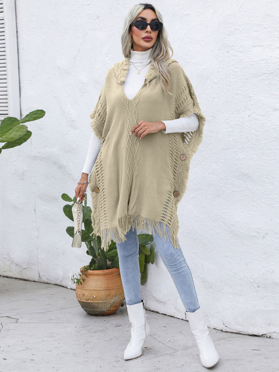 Khaki knit poncho with fringe, wooden buttons, and textured pattern.