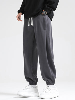 Dark gray relaxed fit sweatpants with white drawstring and cuffed ankles.