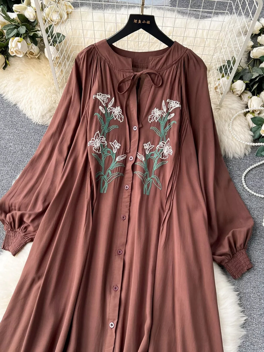 Brown cotton maxi dress with embroidered floral detail and tie neck.