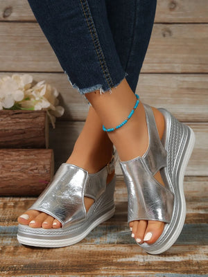Silver metallic wedge sandals with crisscross detail and ankle strap.