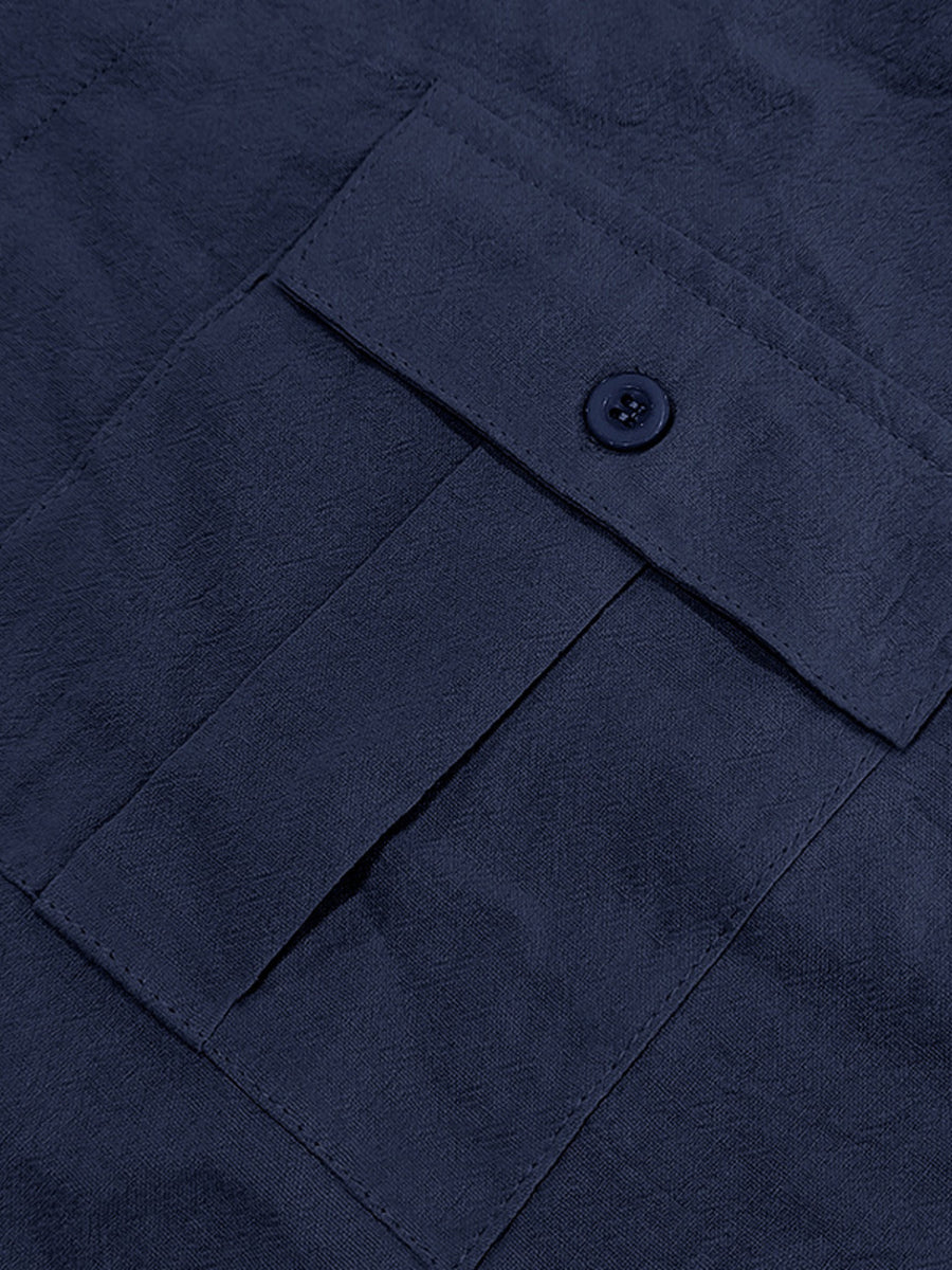 Navy blue button-down shirt detail showing a pocket with a button closure and textured fabric.