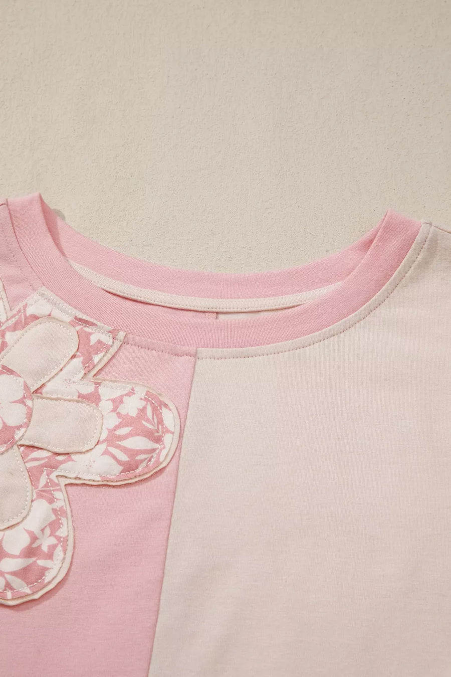Maternity t-shirt with pink and cream color block, featuring a dimensional applique flower detail.
