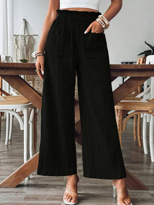 Black textured wide-leg palazzo trousers with ruffled waist and pockets.