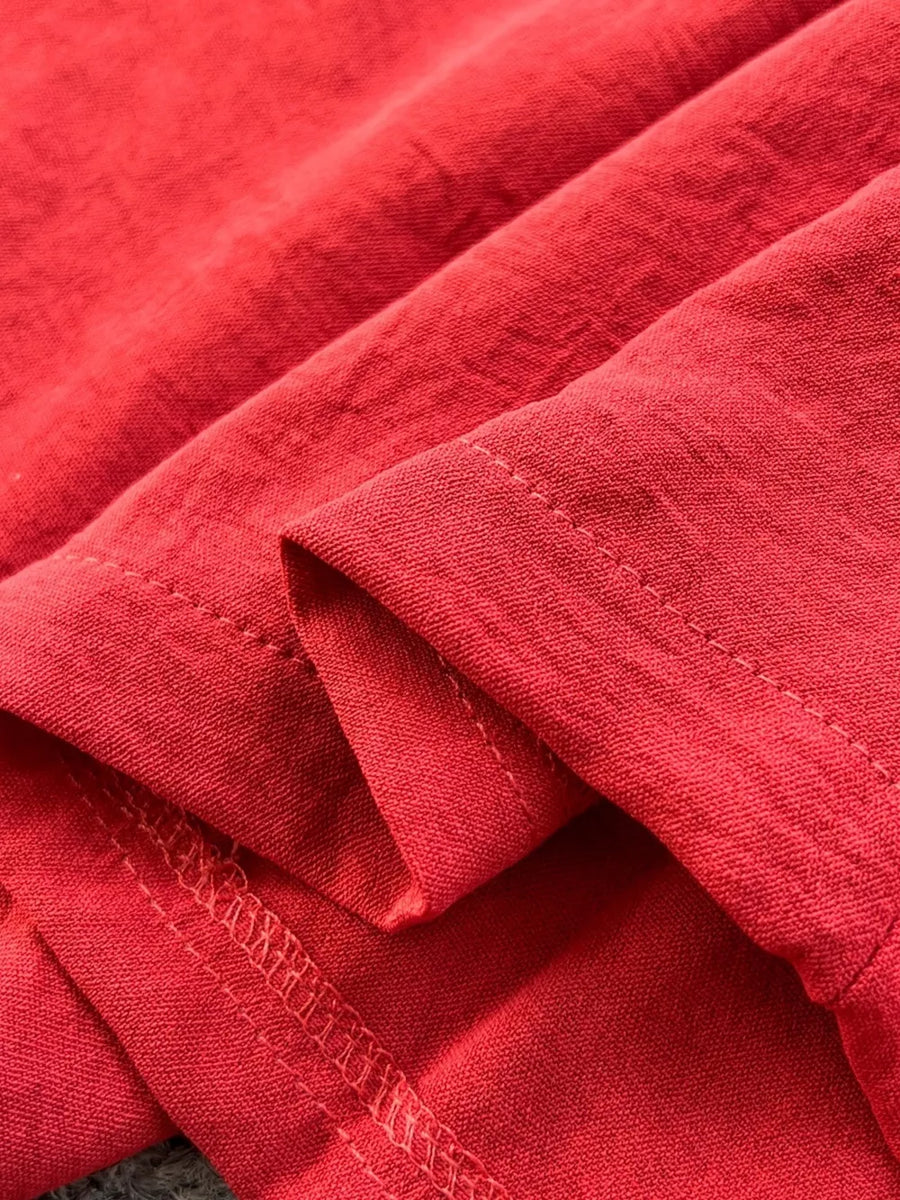 Red belted wide leg romper detail showing textured fabric and stitching.