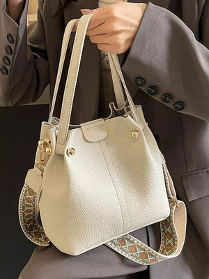 Textured crossbody bag in Rice White with a unique patterned strap and top handles.