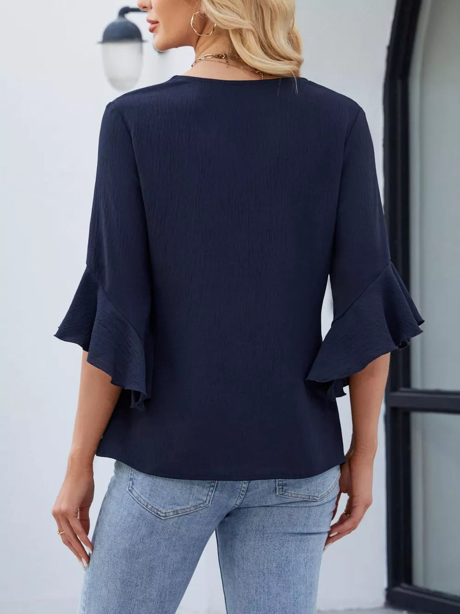 Navy V-neck blouse with ruffle sleeves and textured fabric.