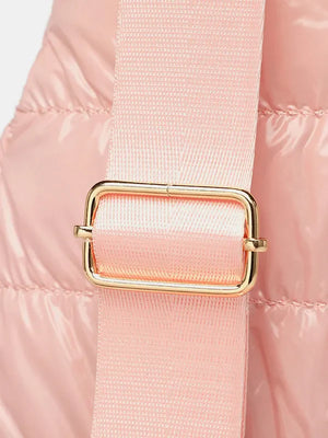 Glossy pink padded sling bag with adjustable strap and gold buckle detail.