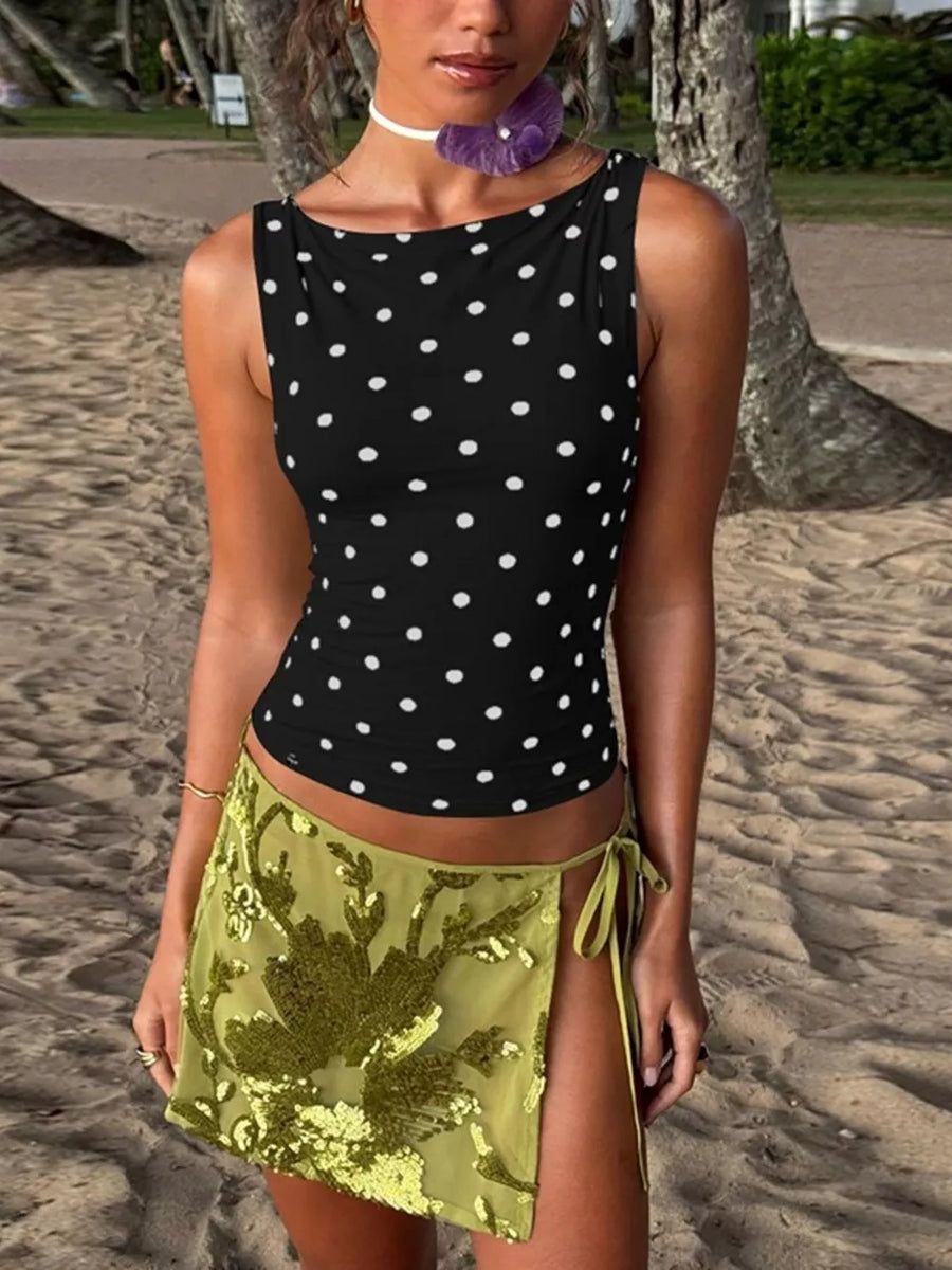 Black polka dot tank top with a scoop neck, paired with a green sequined mini skirt.