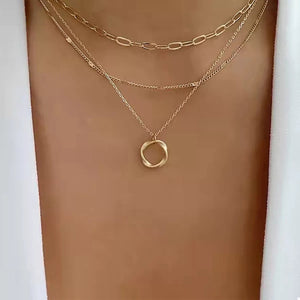 Gold layered necklace with delicate chains and a twisted circle pendant