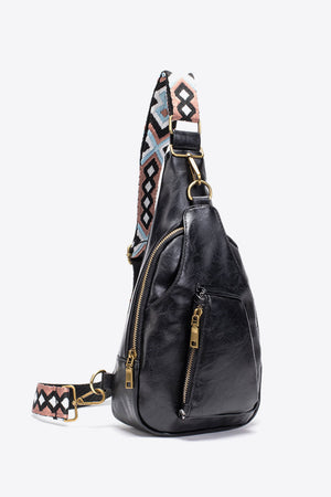 Black textured sling bag with woven geometric strap detail and gold zippers