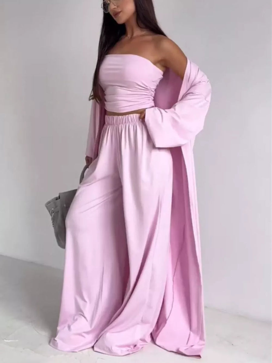 Chic blush pink three-piece maternity set with ruched strapless crop top, wide-leg pants, and flowing cardigan.