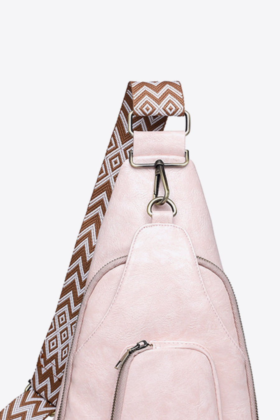 Blush pink PU sling bag with a patterned strap and zipper detail.