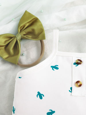 White baby bodysuit with cactus print and button detail, paired with a green bow headband.