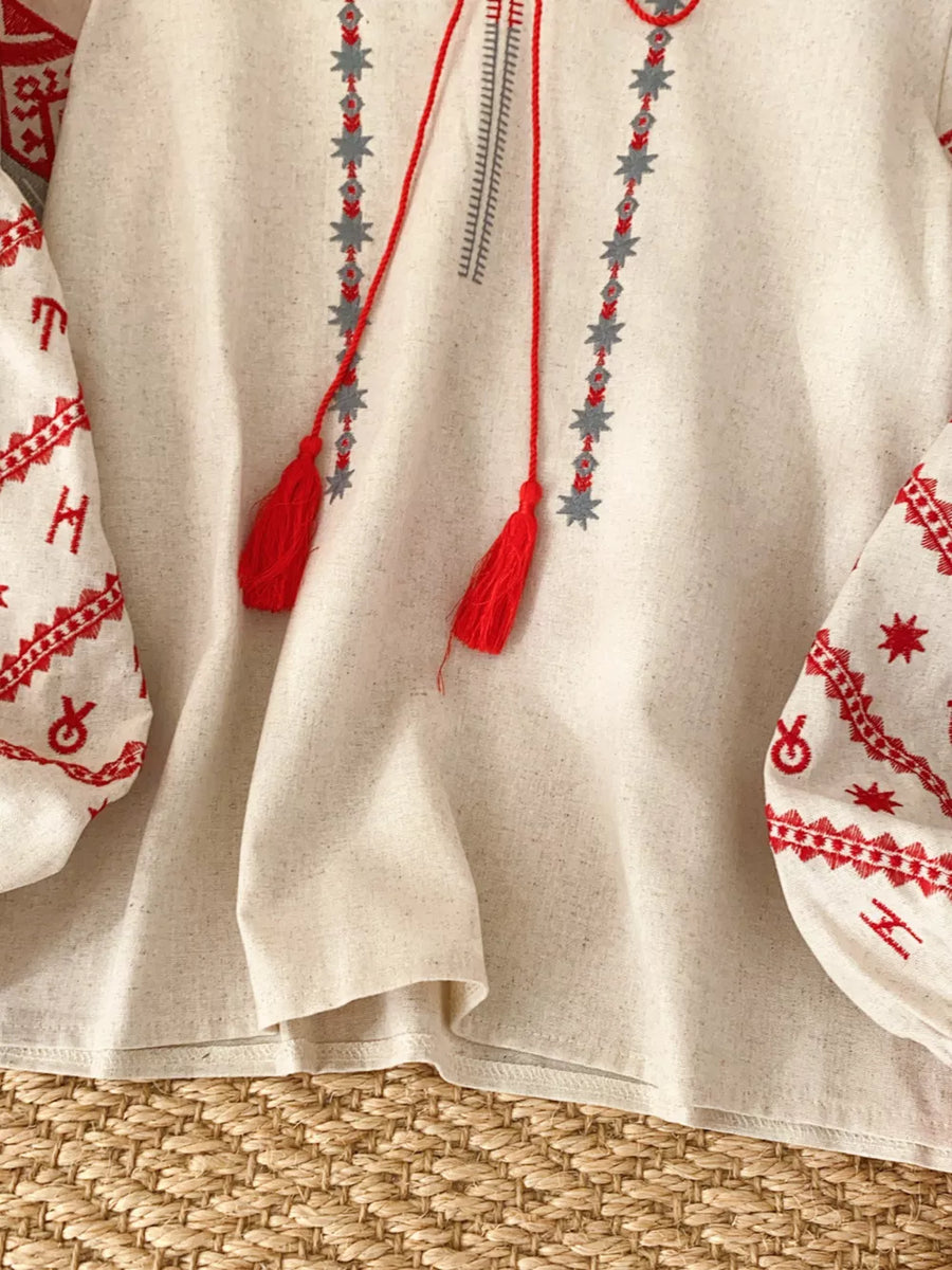 Cream folk-inspired tie neck shirt with red embroidery and tassels.