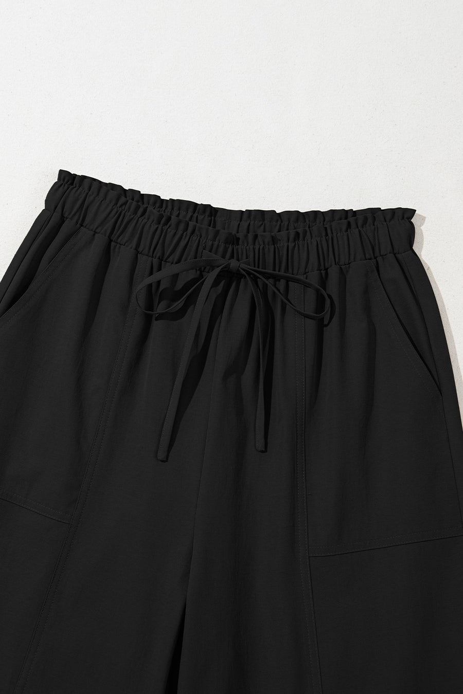 Black cropped drawstring pants with elastic waist and pockets.