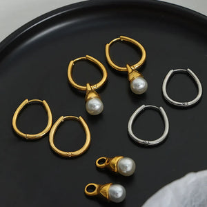 Gold and silver oval hoop earrings with pearl drops.