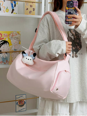 Blush pink travel pouch bag with adjustable strap and exterior pockets, featuring a cute plush charm.