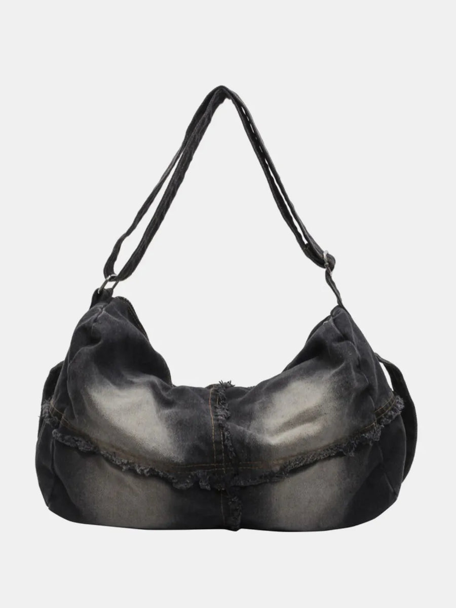 Frayed denim slouch crossbody bag in dark wash with distressed details.