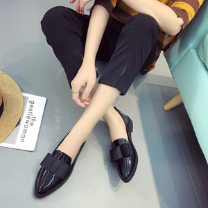 Black patent leather loafers with bow detail.