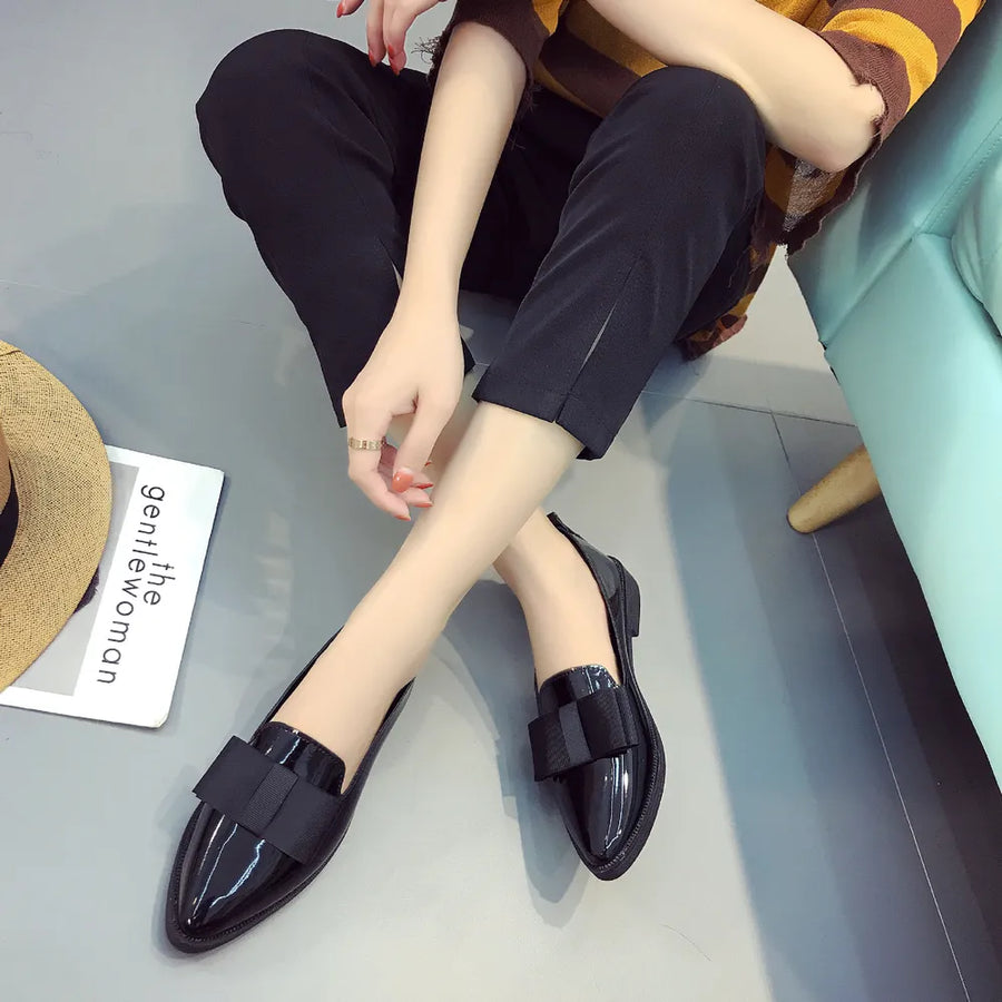 Black patent leather loafers with bow detail.