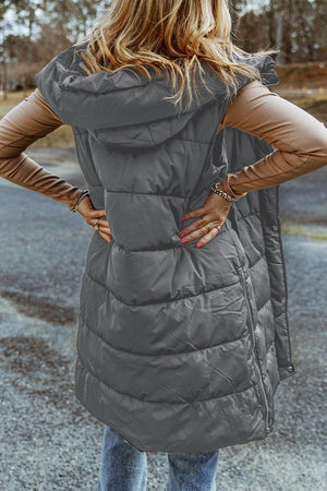 Longline hooded puffer vest in charcoal with horizontal quilting and a side zipper detail.
