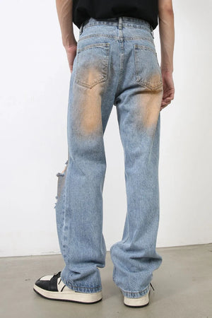 Light blue faded wash wide leg jeans with distressed details and orange bleach accents.