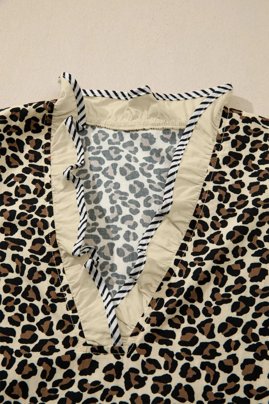 Leopard print mini dress with ruffle trim and striped neckline detail.