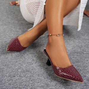 Burgundy croc-embossed pointed toe flare heel mules with an ankle bracelet.