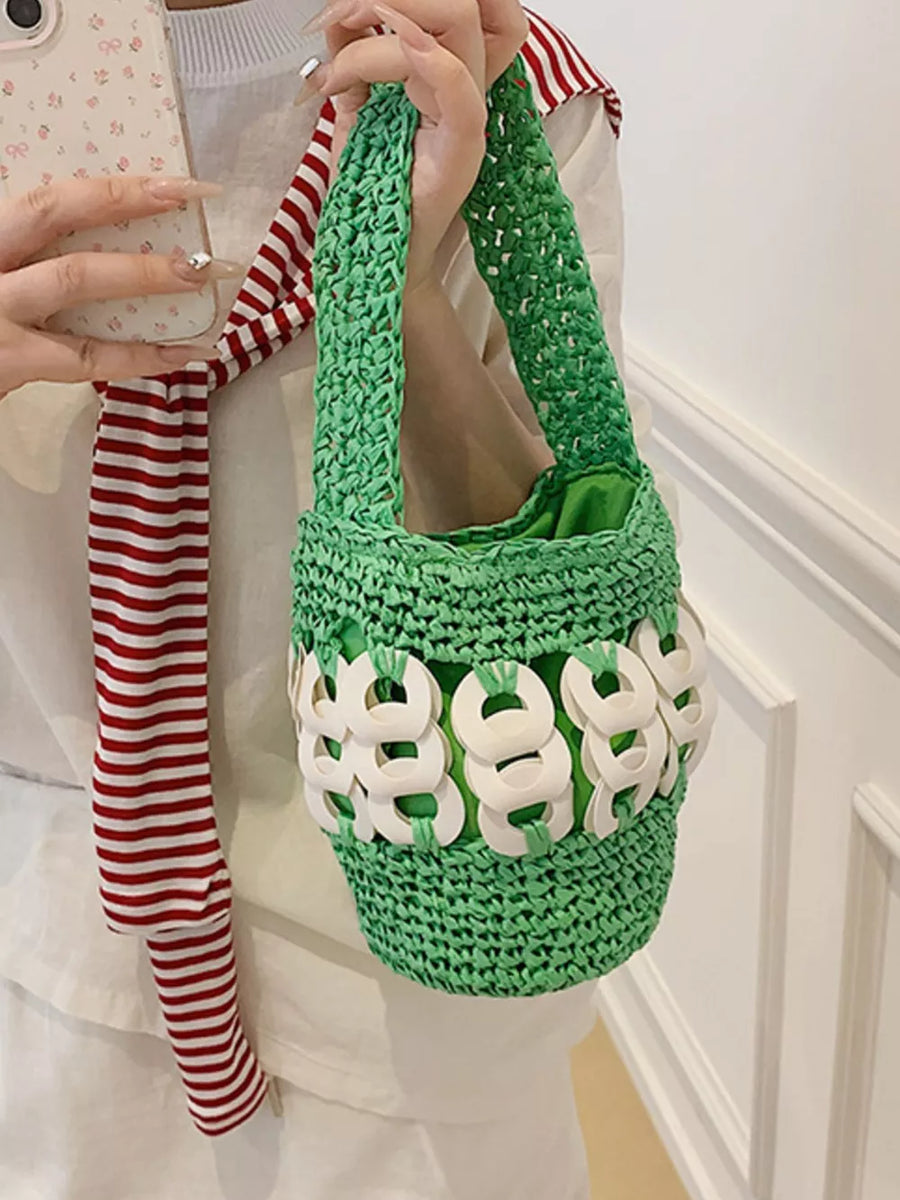 Green woven straw bucket tote with white ring embellishments and green lining.