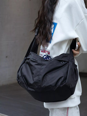 Black nylon crossbody bag with adjustable strap and exterior pockets.