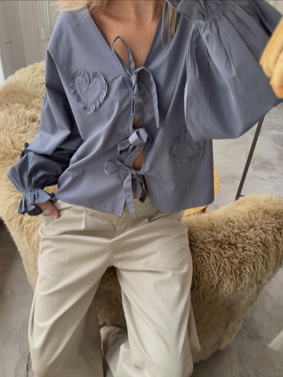 Gray tie-front blouse with heart appliqué details and ruffled cuffs.