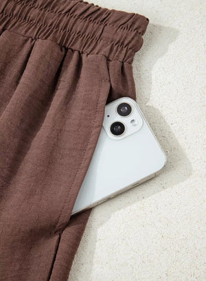 Brown maternity trousers with drawstring detail and a phone in the pocket.