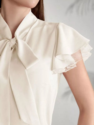 Beige tie-neck blouse with ruffle sleeves featuring lace trim.