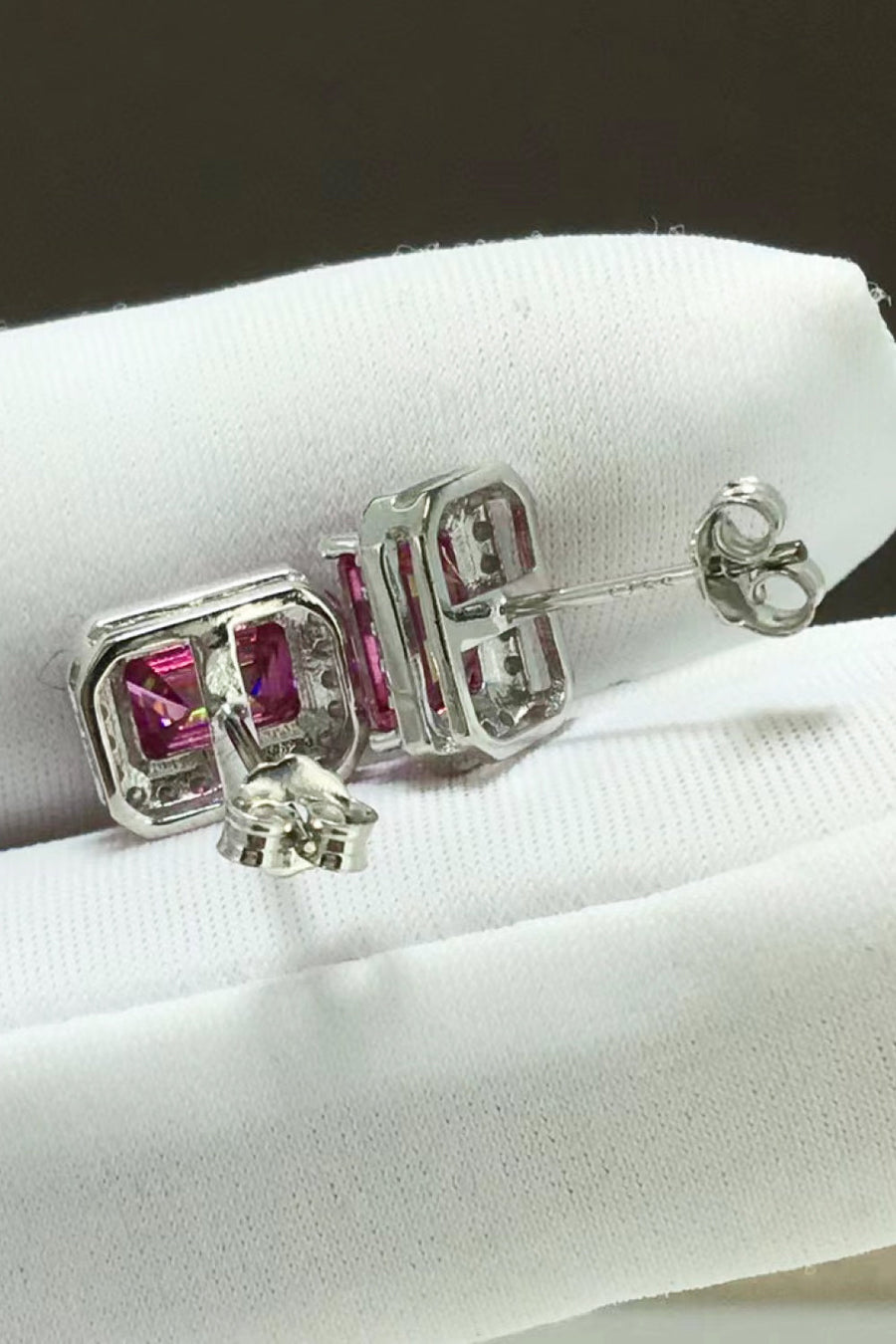 Emerald cut moissanite halo stud earrings in rose gold with diamond accents.