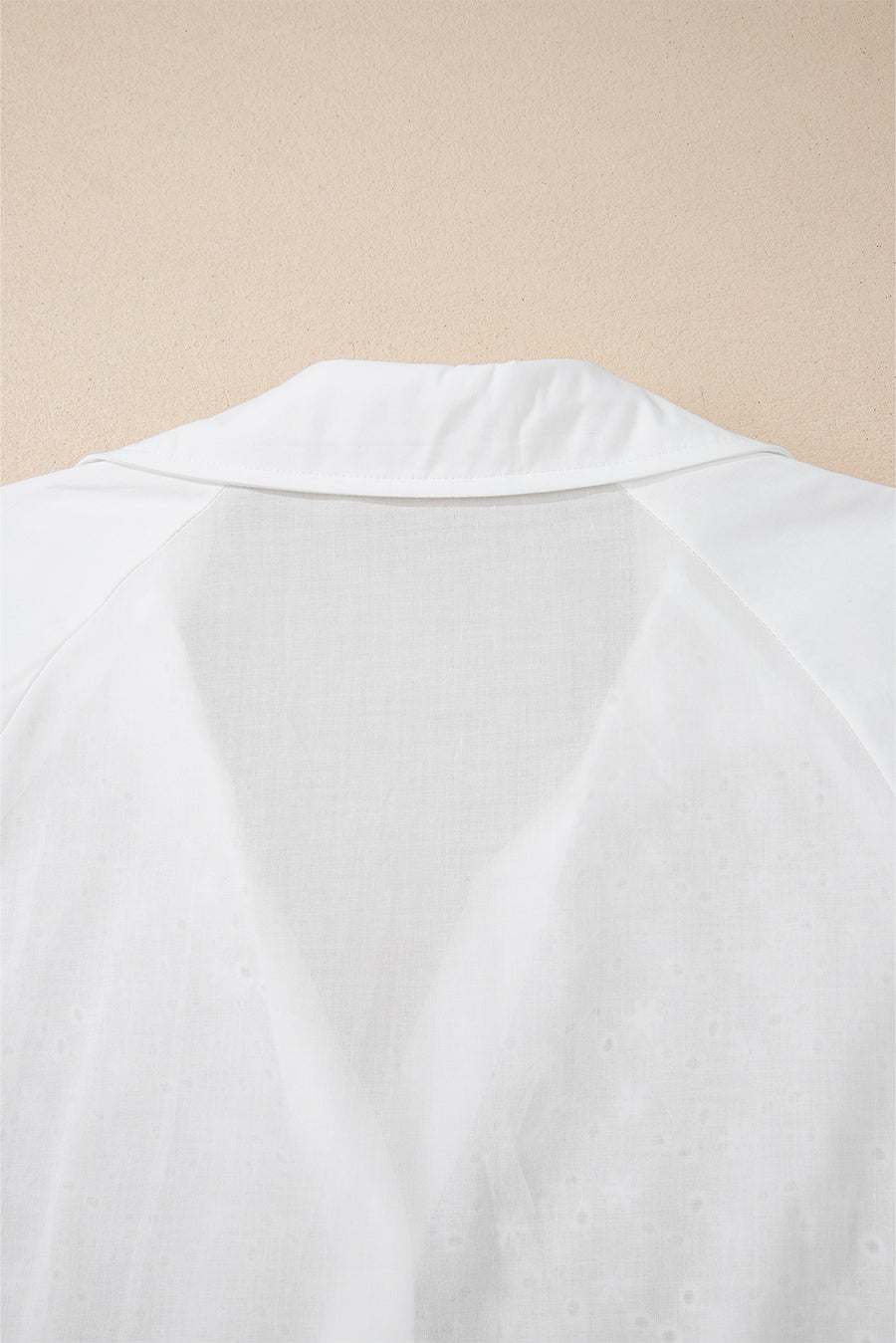 White embroidered eyelet blouse with a collared neckline and poet sleeves.