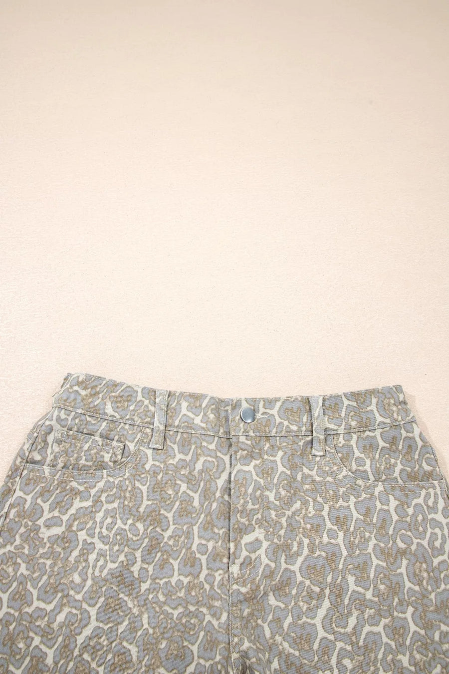 Denim shorts with a subtle leopard print in grey and tan, featuring a button fly and front pockets.
