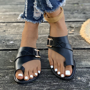 Chic black toe loop flat sandals with gold buckles and crisscross straps.