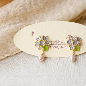 Floral pearl drop earrings with light blue flowers and pink pearls.